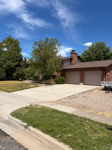 Brick exterior with a prominent chimney, a two-car garage, and a concrete driveway
