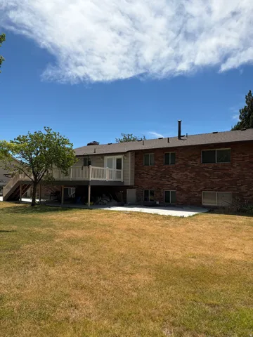 Spacious backyard featuring a multi-level deck, brick exterior, and a lower-level concrete patio