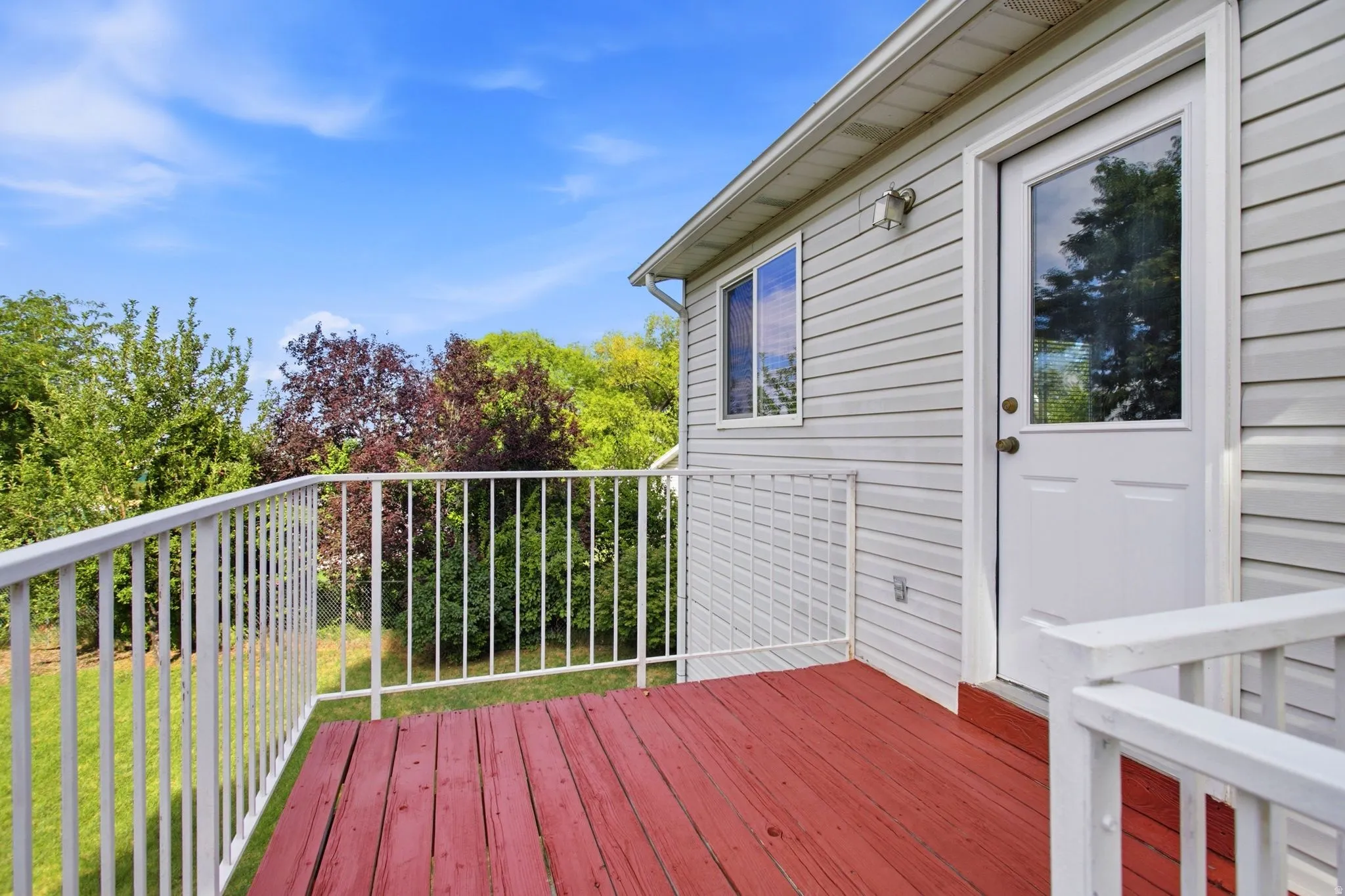 Exterior deck with wood decking, white metal railing, and light-colored siding