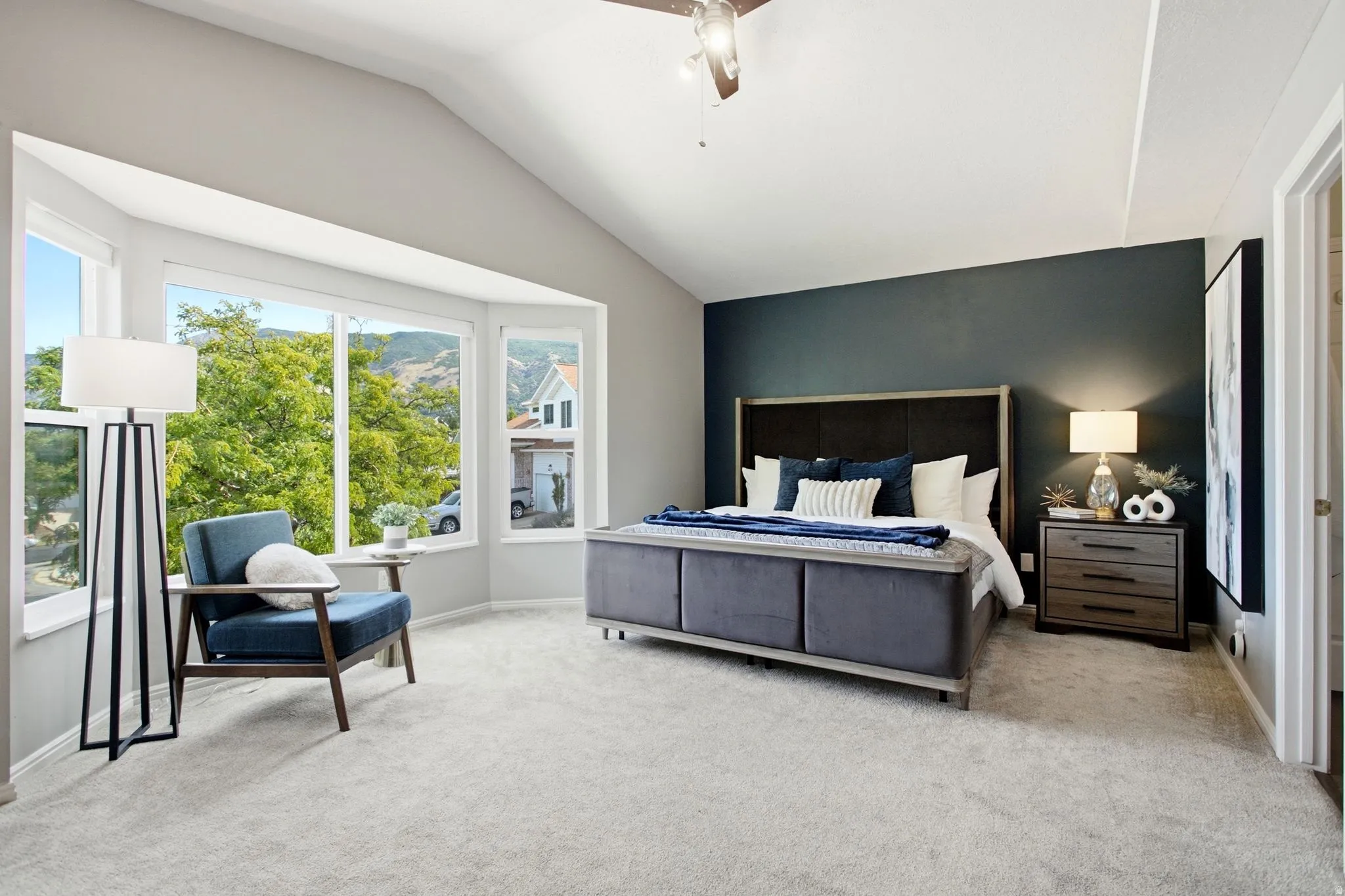 Vaulted ceiling, bay window, light gray carpet, recessed lighting, and a ceiling fan