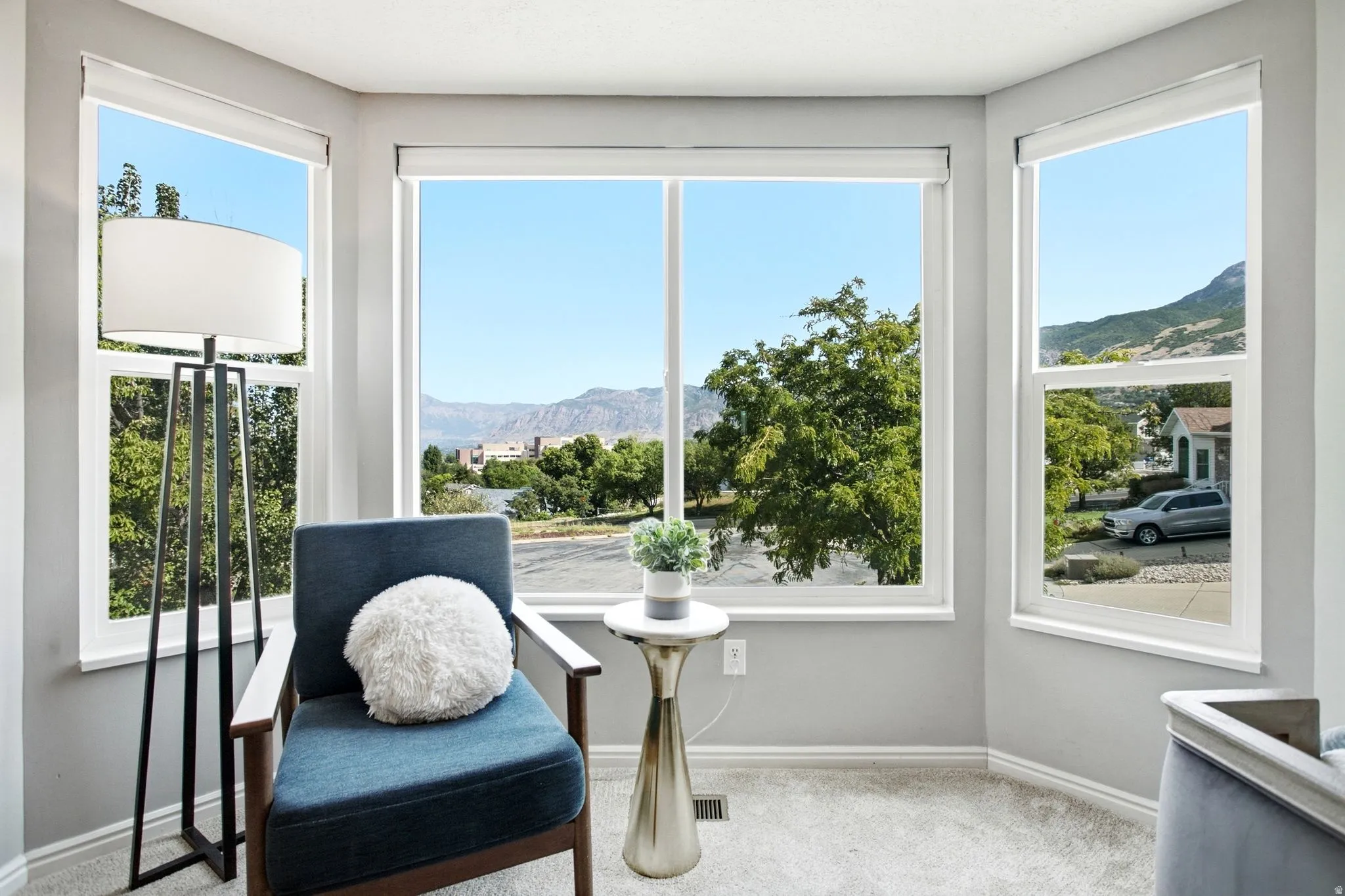 Bay window with multiple large glass panes, white window frames, and roller shades