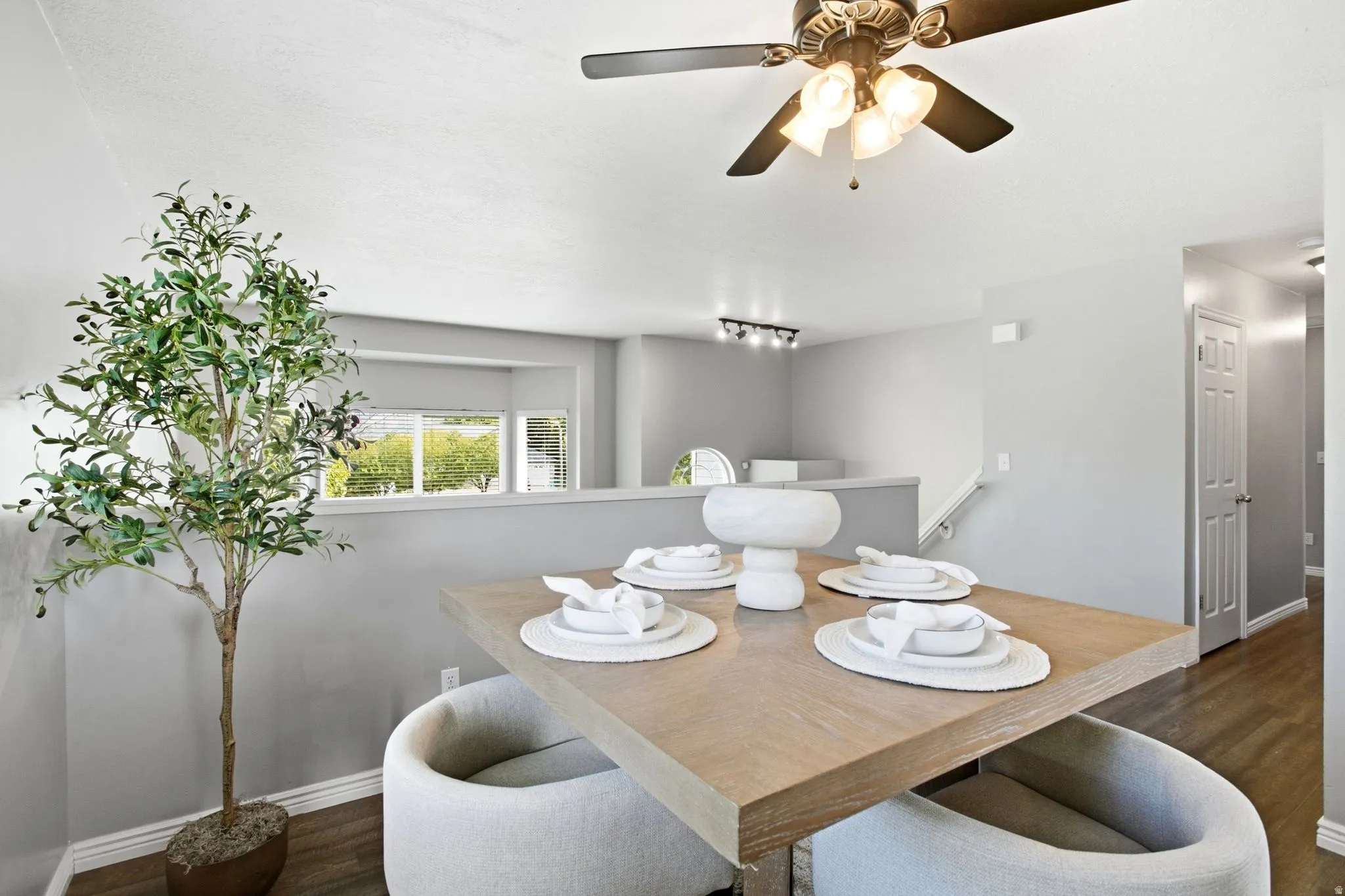 Recessed dining area with a wood-finish table, multi-pane windows, and a ceiling fan with integrated lighting