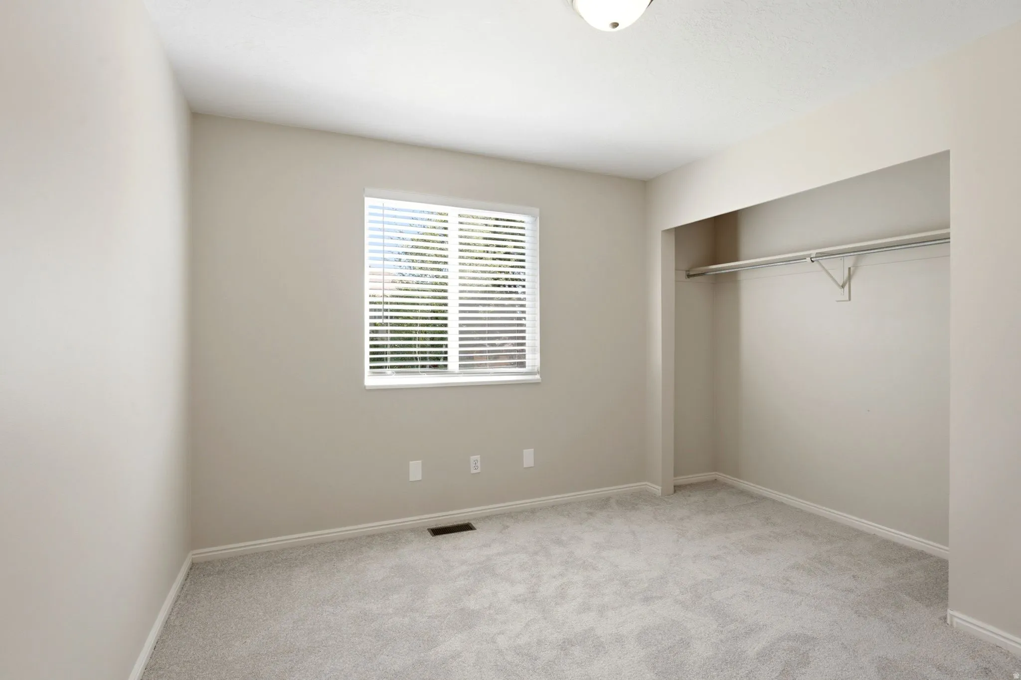 Bedroom featuring neutral wall paint, light gray carpeting, and a window with blinds