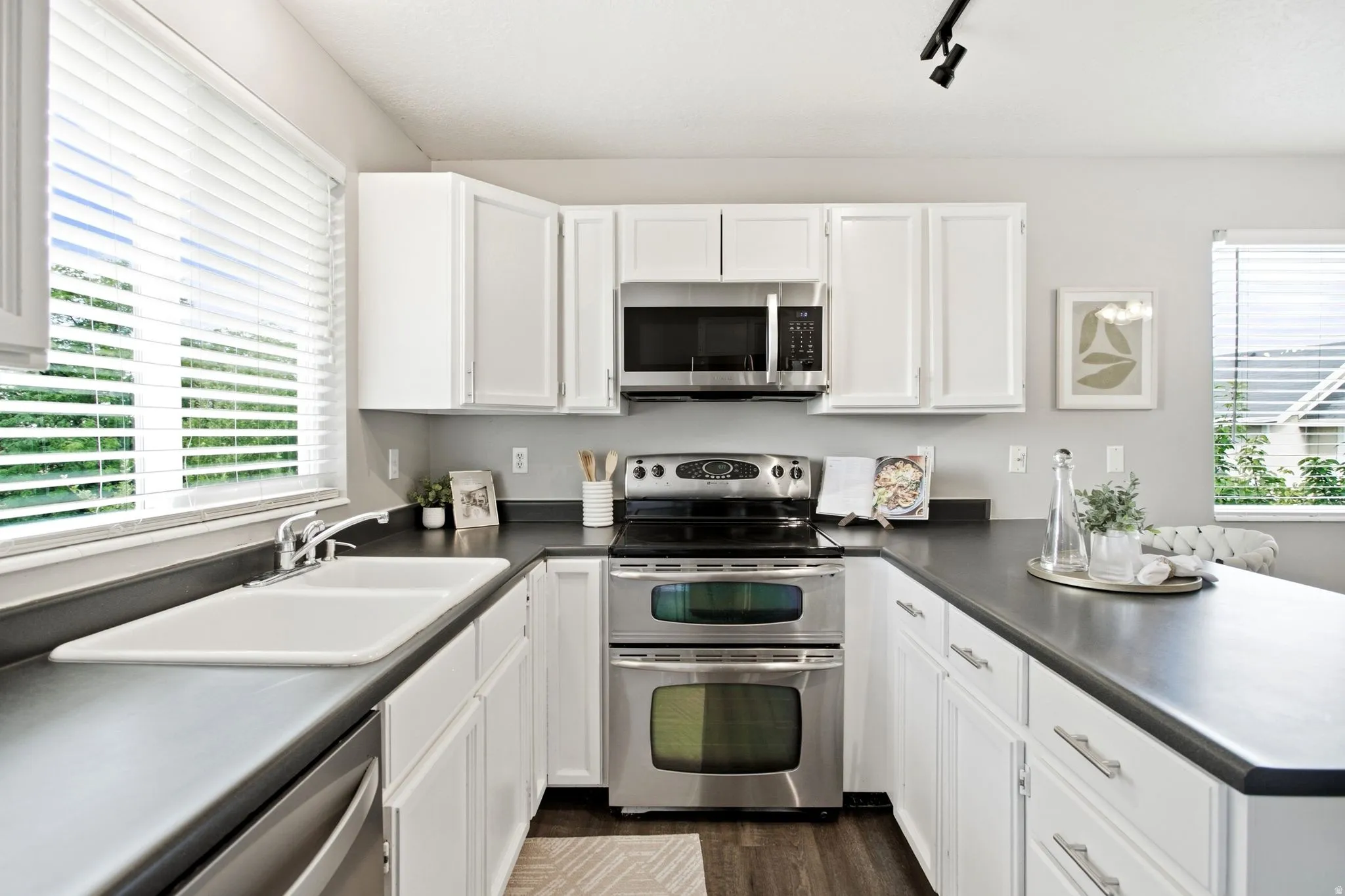 Modern kitchen featuring white cabinetry, stainless steel dual wall ovens, gas cooktop, and black quartz countertops