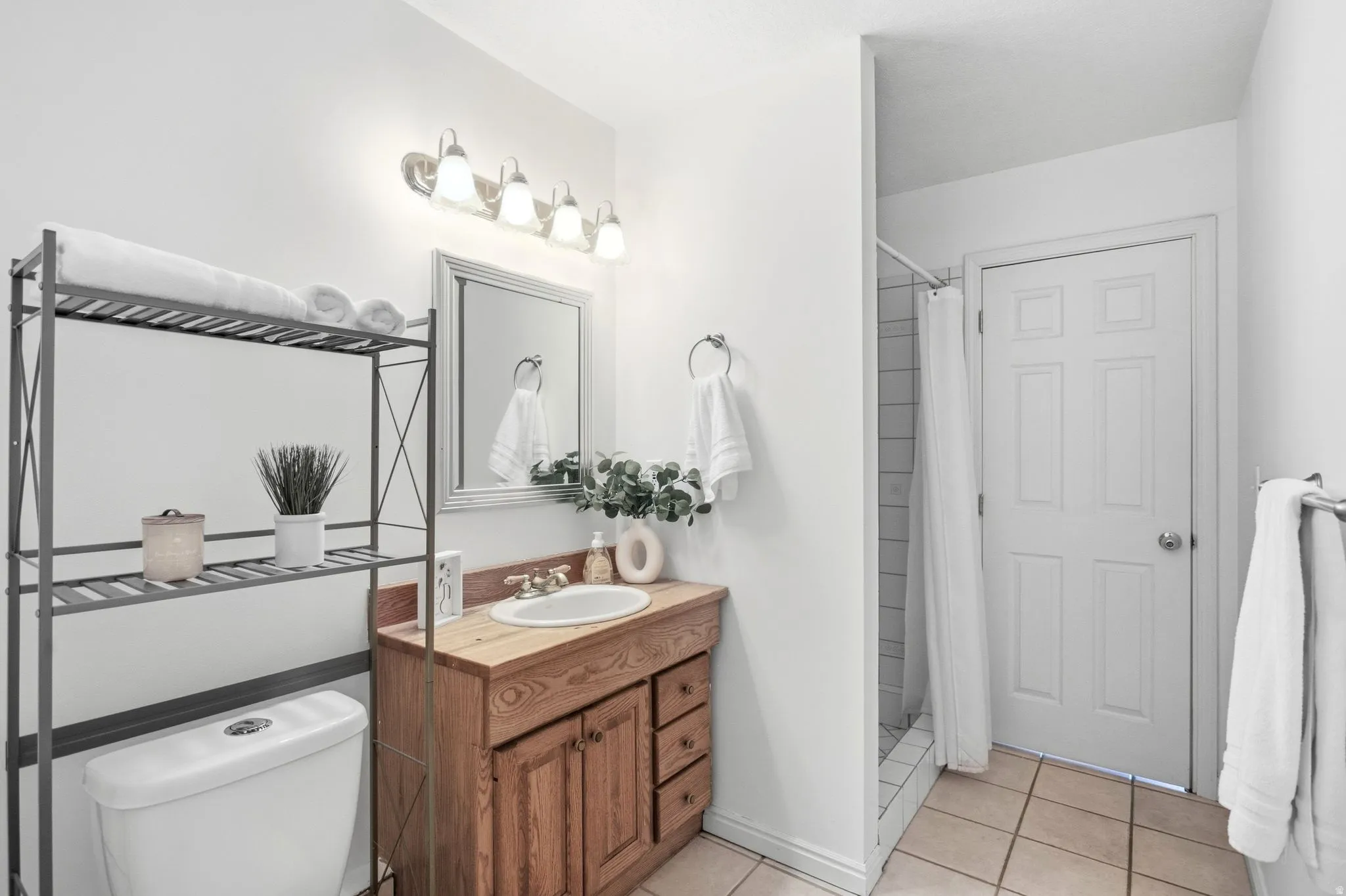 Wood-finish vanity with an integrated sink, framed mirror, and a four-light fixture