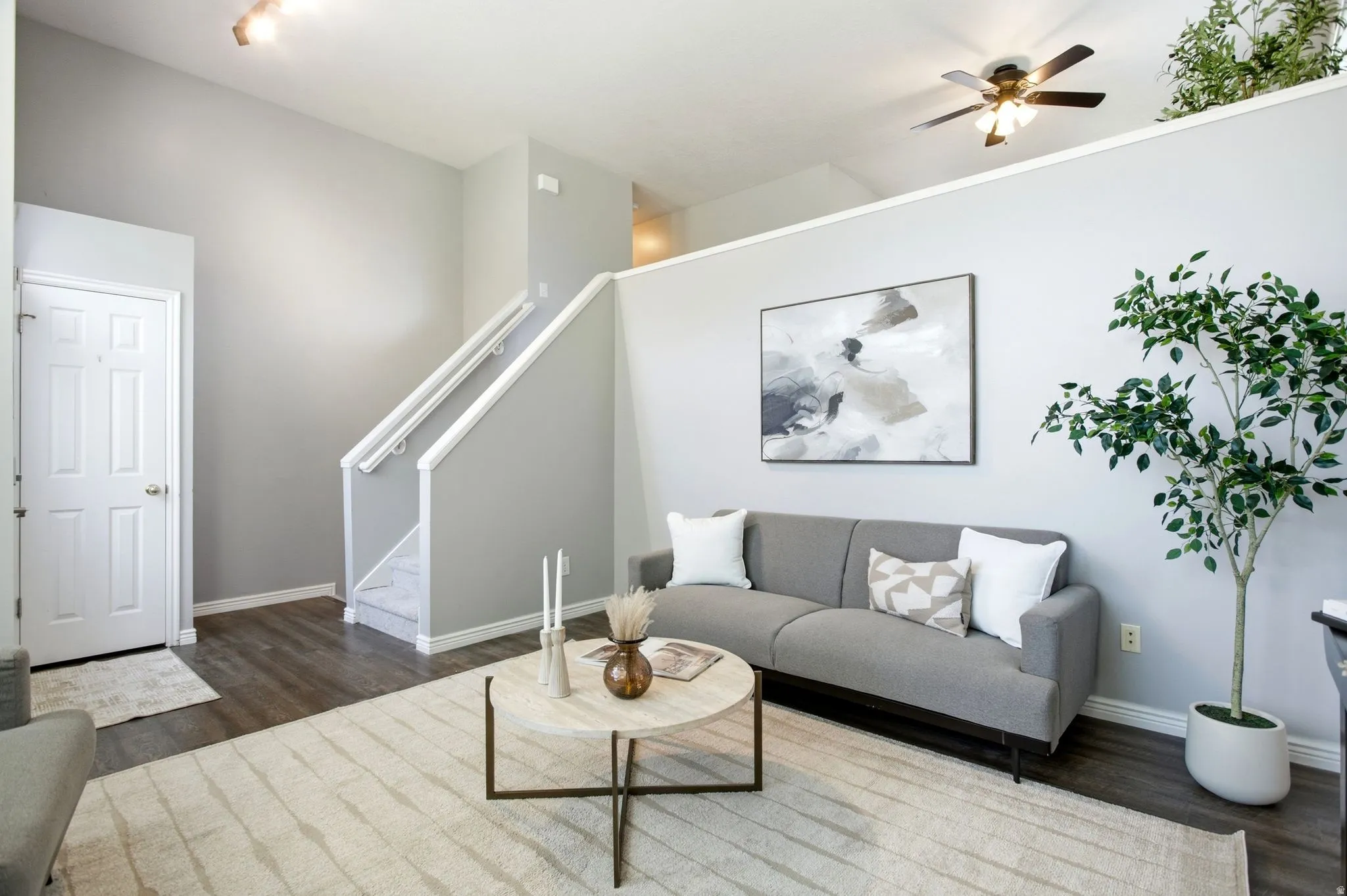 Open-concept living area with vaulted ceilings, wood-finish flooring, and a ceiling fan