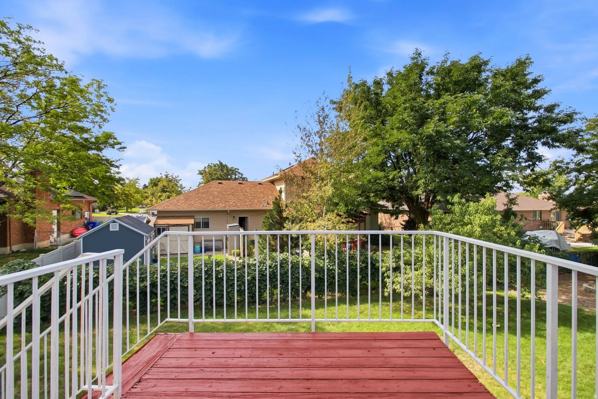Elevated composite deck with rich wood-finish decking and white aluminum railings overlooking a manicured lawn