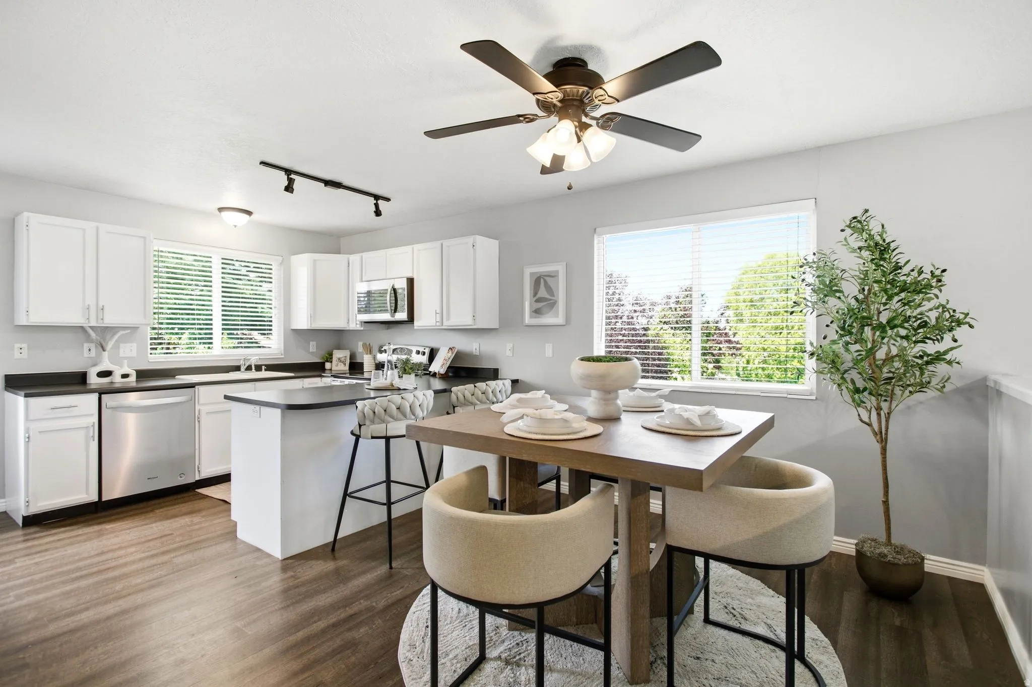 Kitchen featuring white cabinetry, stainless steel appliances, dark countertops, a central island, and wood-finish flooring