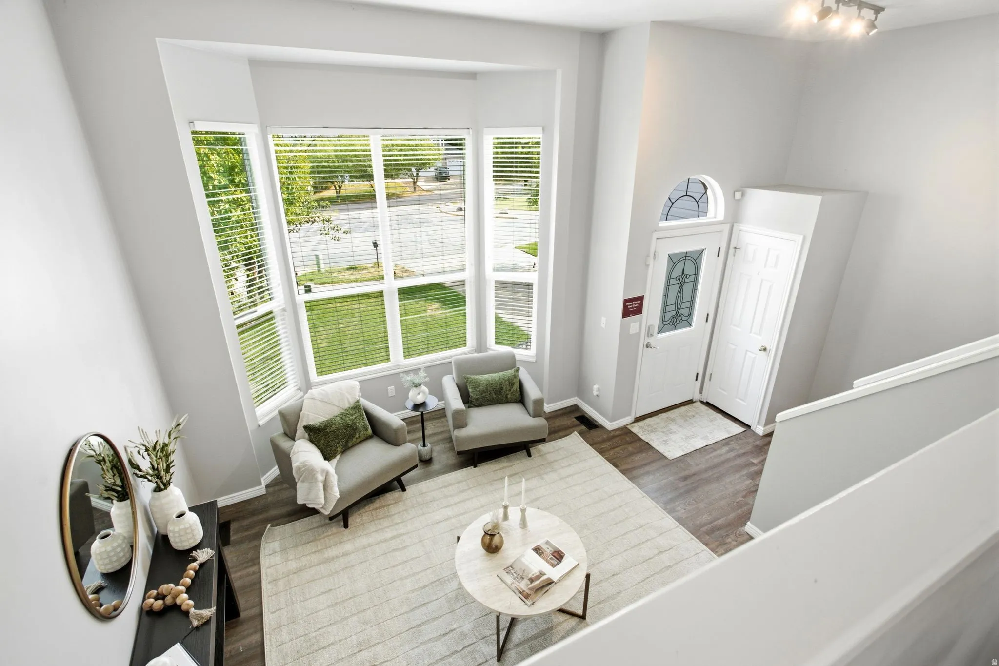 Two-story entry foyer with wood-finish flooring, a decorative front door with an arched transom, and a prominent bay window