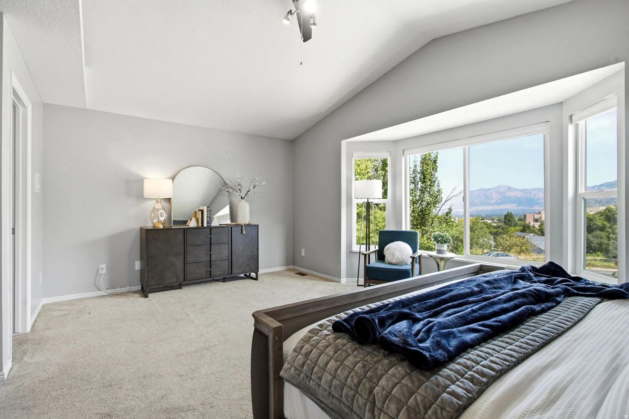 Vaulted ceiling, carpeted flooring, large bay window, expansive mountain scenery, and built-in ceiling fan