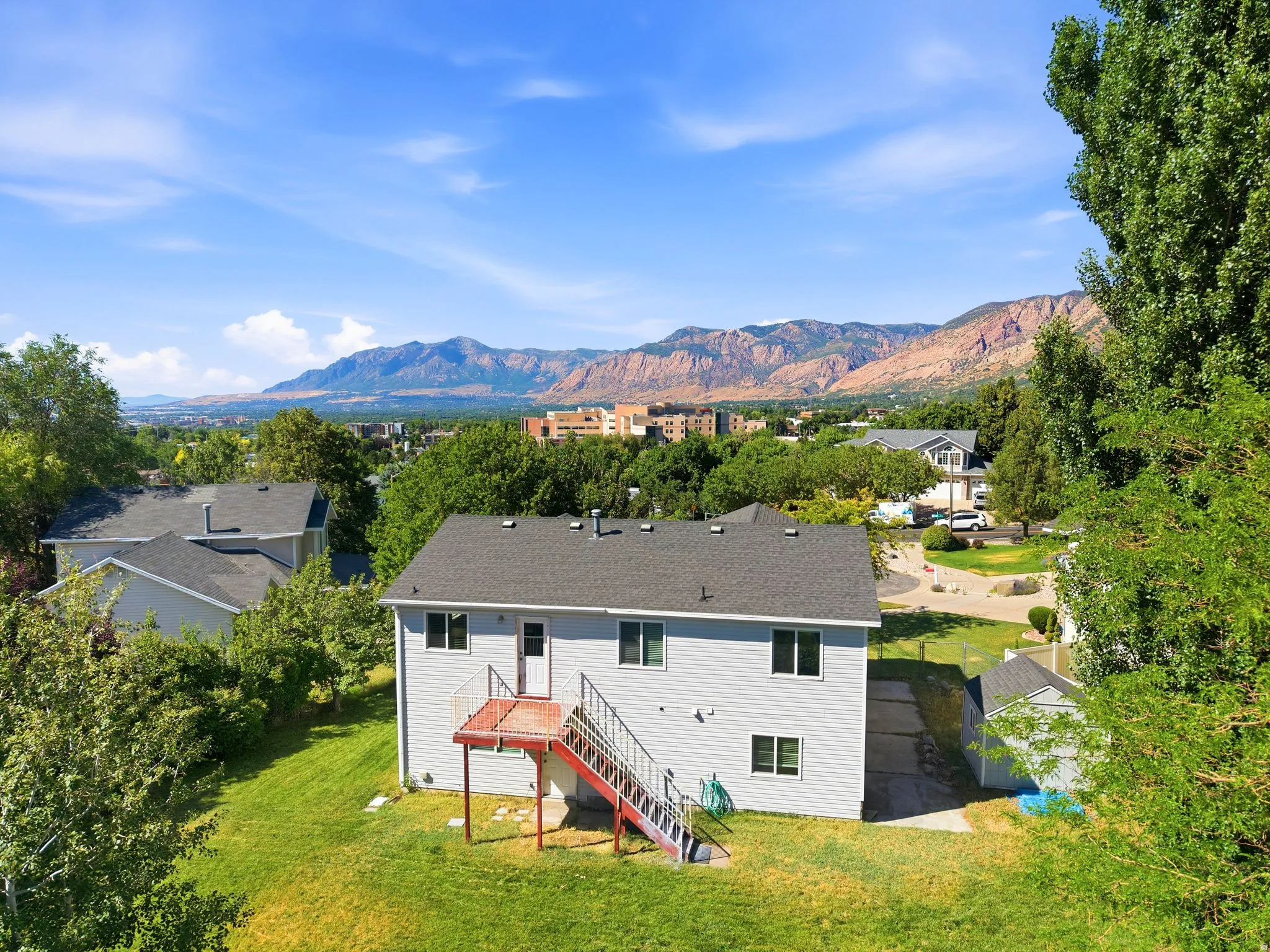 Expansive backyard featuring a manicured lawn, established trees, and a detached shed