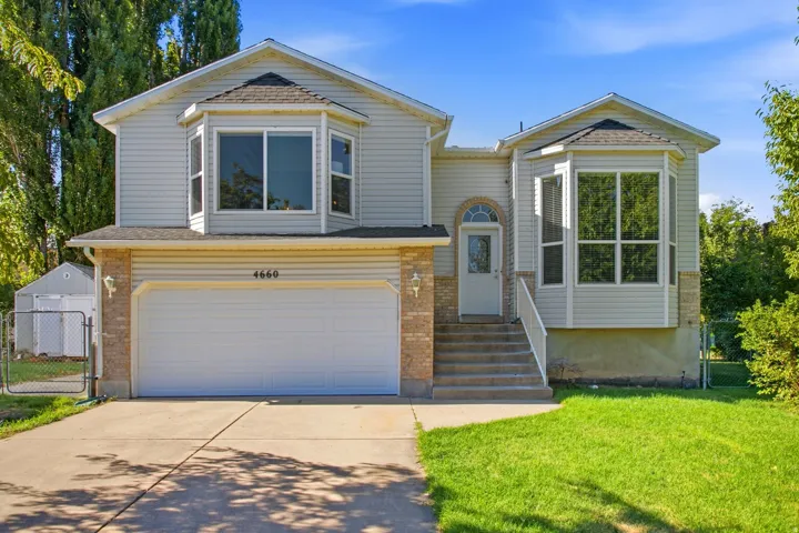Two-story residence featuring light-colored siding, a two-car garage, and multiple bay windows