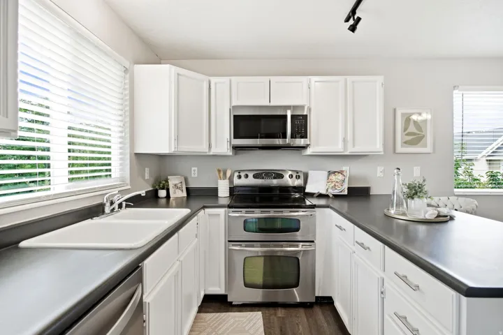 Modern kitchen featuring white cabinetry, stainless steel dual wall ovens, gas cooktop, and black quartz countertops