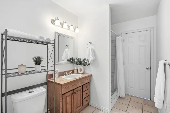 Wood-finish vanity with an integrated sink, framed mirror, and a four-light fixture