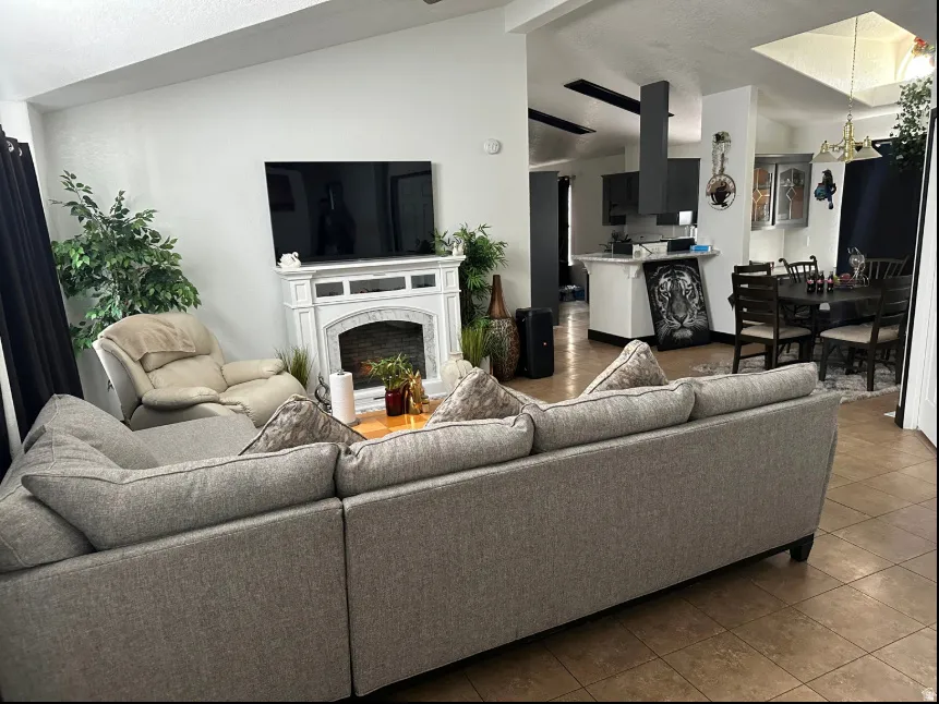 Open-concept living space featuring a white mantel, an integrated kitchen with a dark range hood, and a dining area with a dark wood table