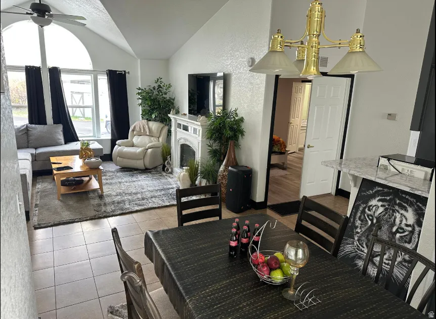 Vaulted ceiling living area featuring a large arched window, a decorative fireplace, and tile flooring