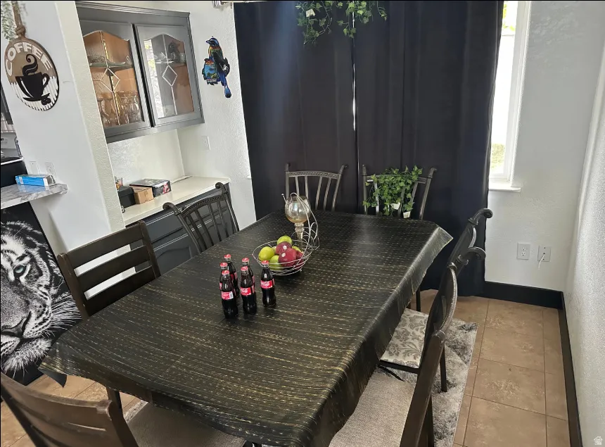 Dining area featuring tile flooring, a built-in cabinet with glass-front uppers, and a window providing natural light