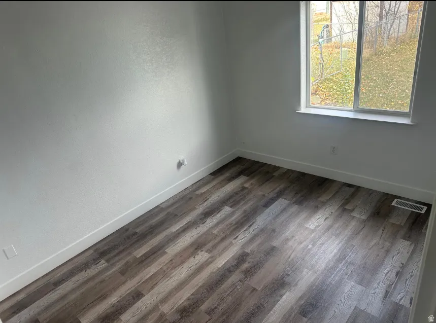 Light-filled room featuring wood-finish flooring, white baseboards, and a double-pane window