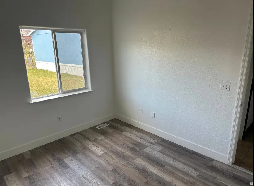 Room featuring wood-finish flooring, crisp white baseboards, and a large window