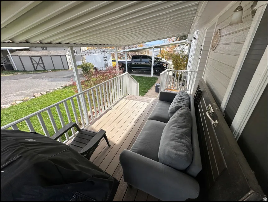 Covered front porch with wood-finish flooring, white railing, and exterior siding