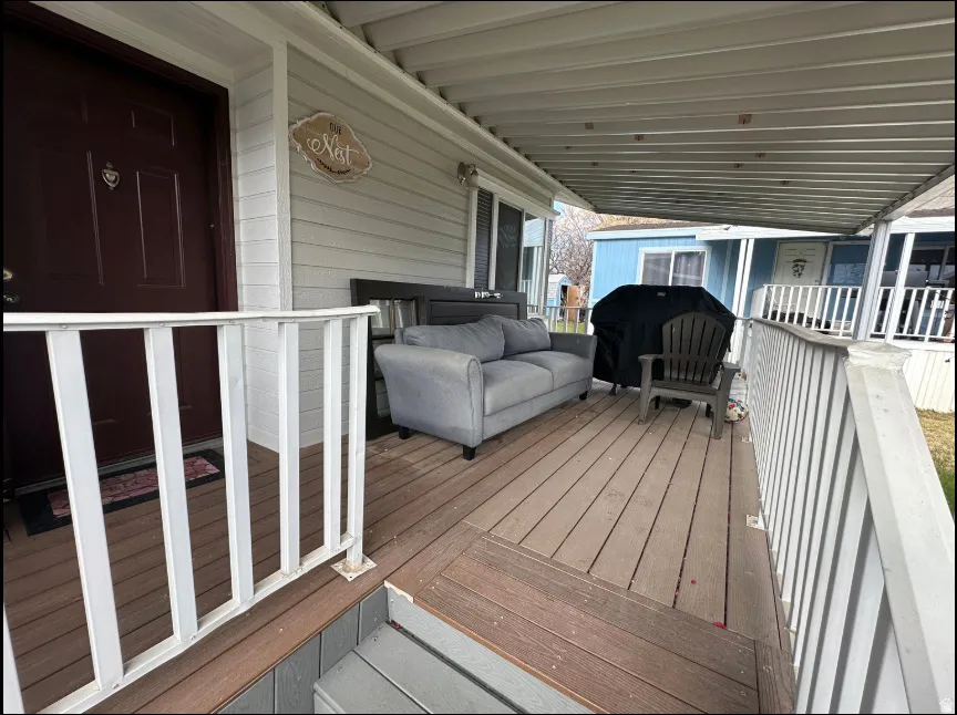 Covered porch featuring wood-finish decking and white railings