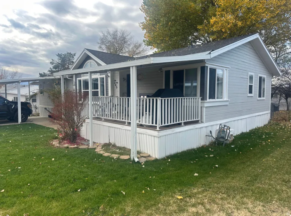 Light gray siding exterior with white trim and a covered front porch featuring white railings