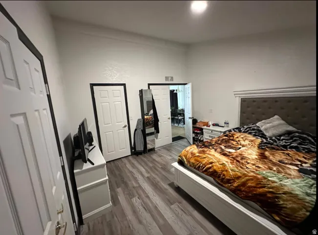Room featuring wood-finish flooring, white walls, and multiple paneled doors with contrasting trim