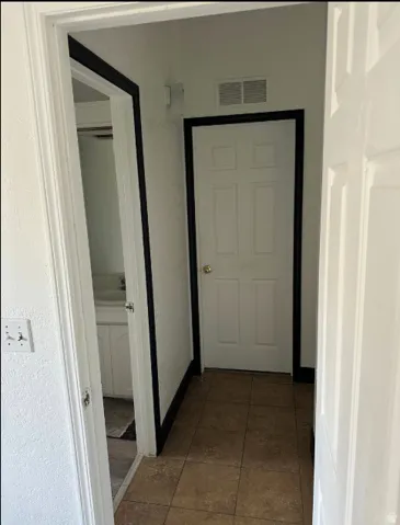 Tiled entryway with paneled doors and white walls