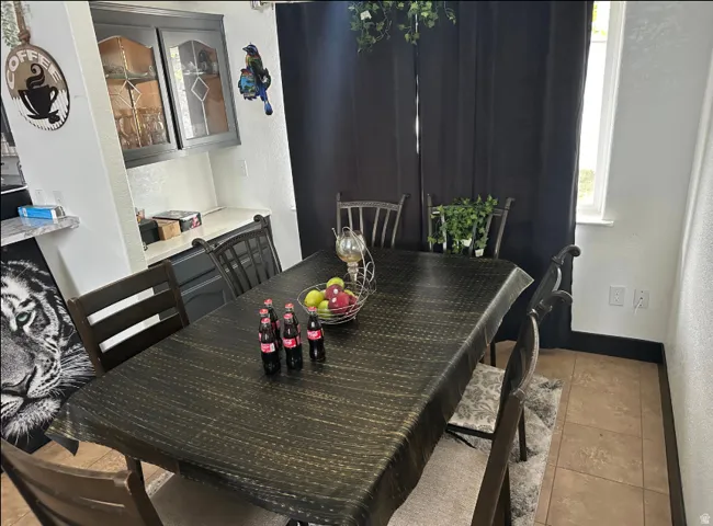 Dining area featuring tile flooring, a built-in cabinet with glass-front uppers, and a window providing natural light