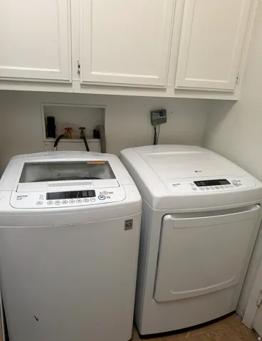 White cabinetry with shaker-style doors, integrated laundry hookups, and neutral-toned flooring