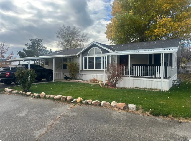 Single-story residence featuring a covered front porch with white railing, a separate covered carport, and a prominent arched window design