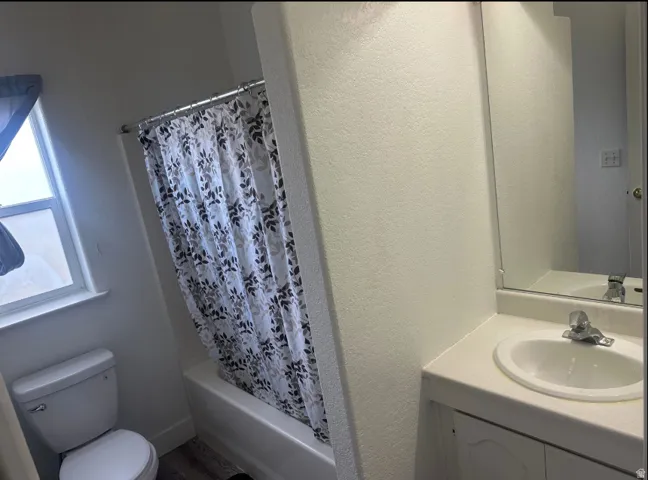 Bathroom featuring a tub/shower combination, white toilet, and a vanity with an integrated sink and mirror