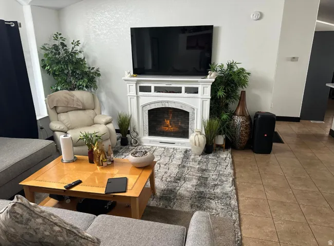 Living room featuring a decorative fireplace with a mantelpiece, light-toned walls, and tile flooring