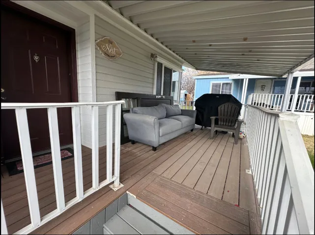 Covered porch featuring wood-finish decking and white railings