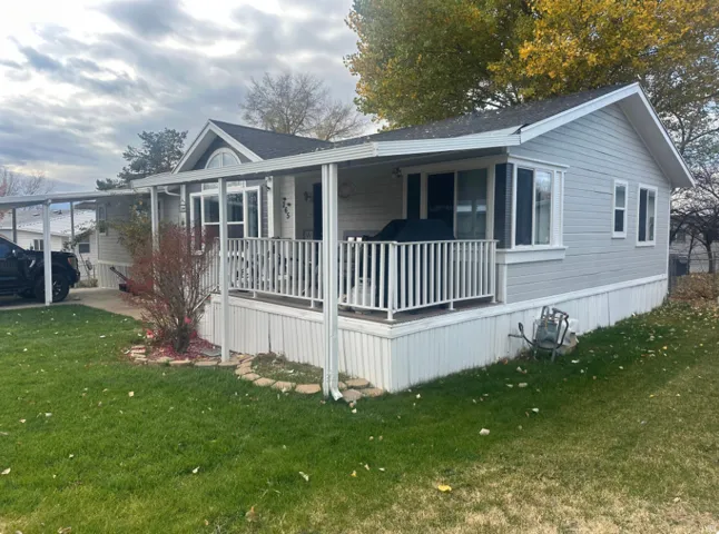 Light gray siding exterior with white trim and a covered front porch featuring white railings