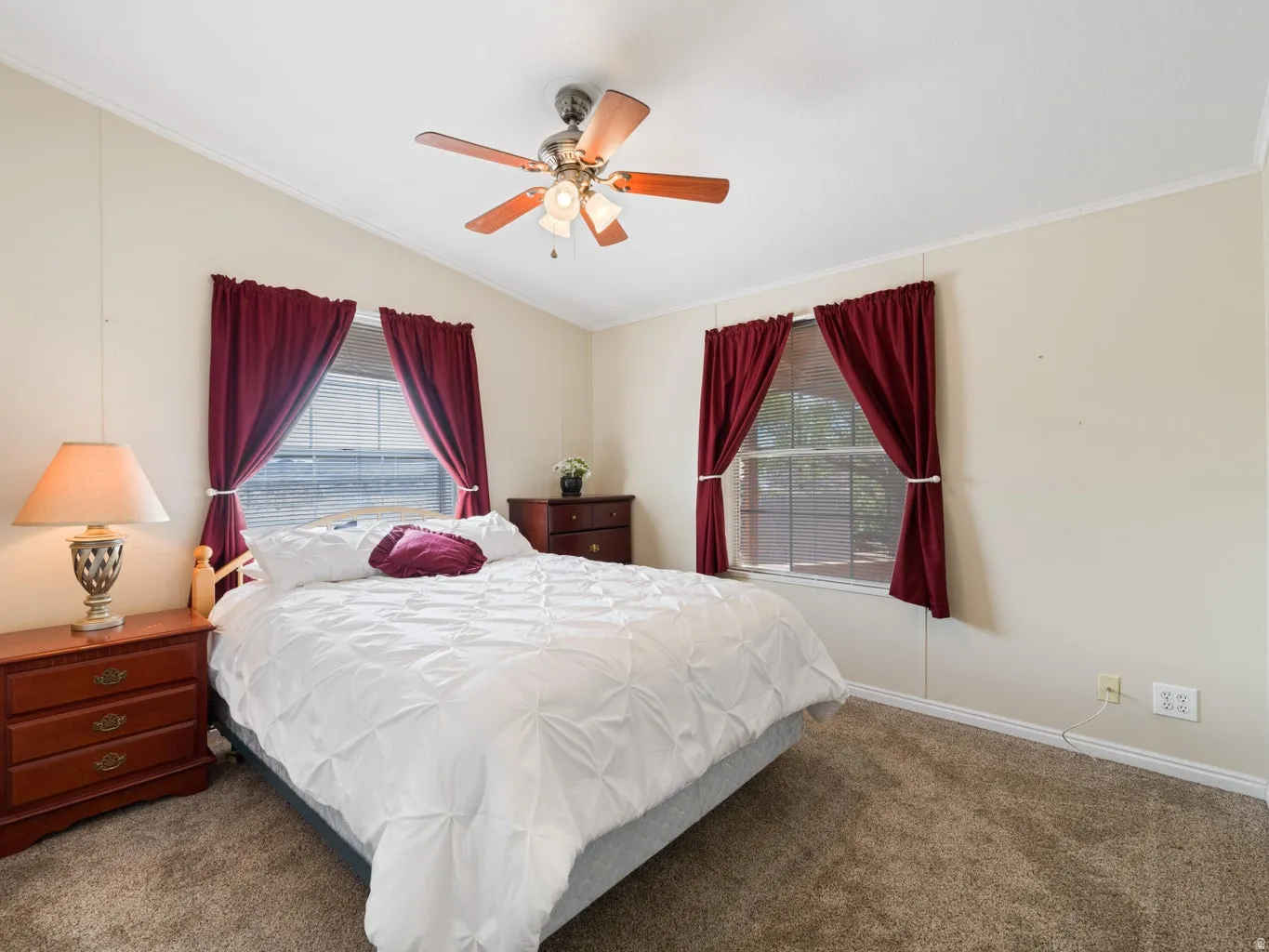 Carpeted room featuring a ceiling fan with integrated lighting, two windows with blinds, and white baseboards