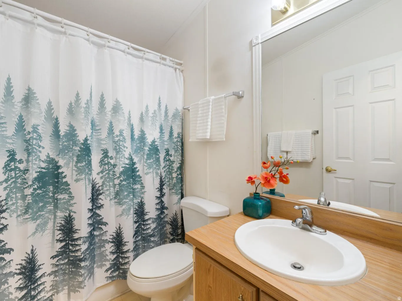 Bathroom featuring a wood-finish vanity with an integrated sink, polished chrome faucet, and a large wall-mounted mirror