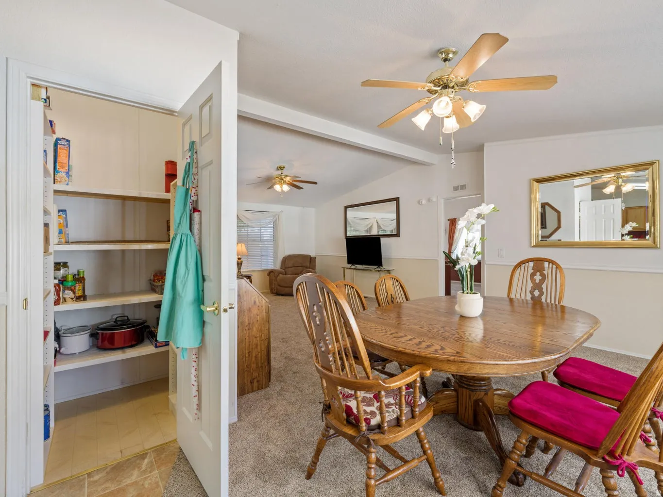 Dining area with wood-finish flooring, a ceiling fan with integrated lighting, and a pantry with built-in shelving