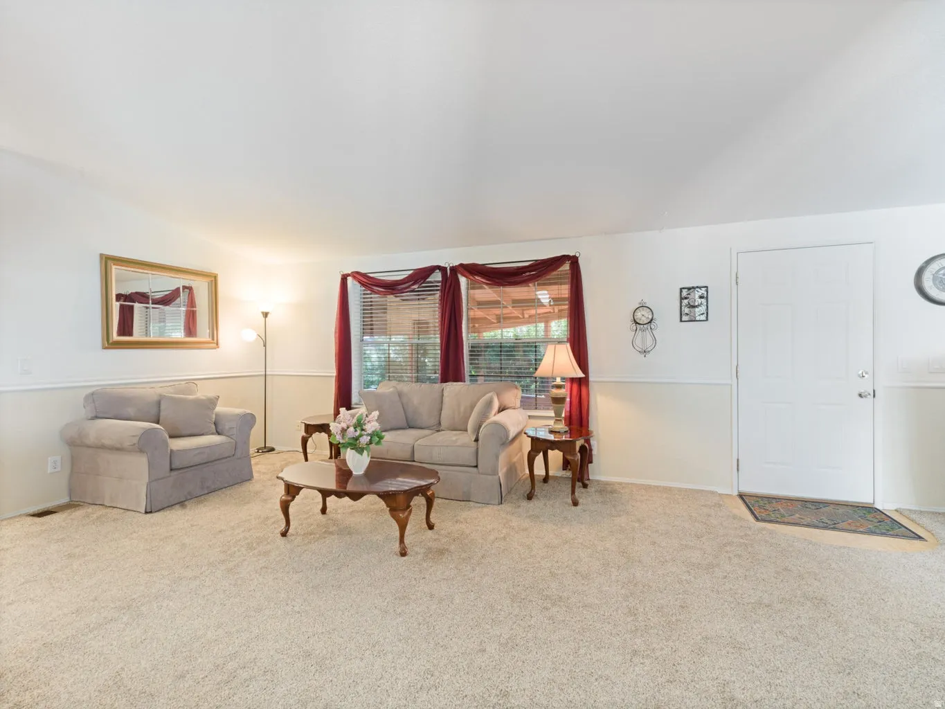 Carpeted living area featuring a two-tone wall treatment with chair rail molding and a paneled entry door