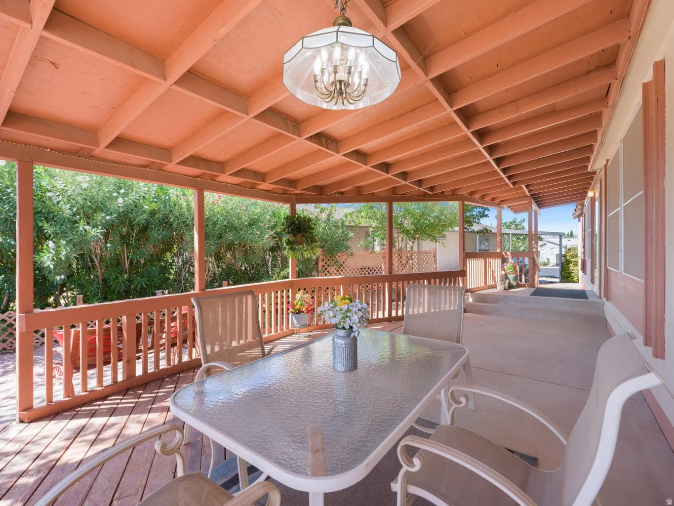 Covered outdoor living space featuring a wood-finish ceiling, exposed beams, and a chandelier-style light fixture