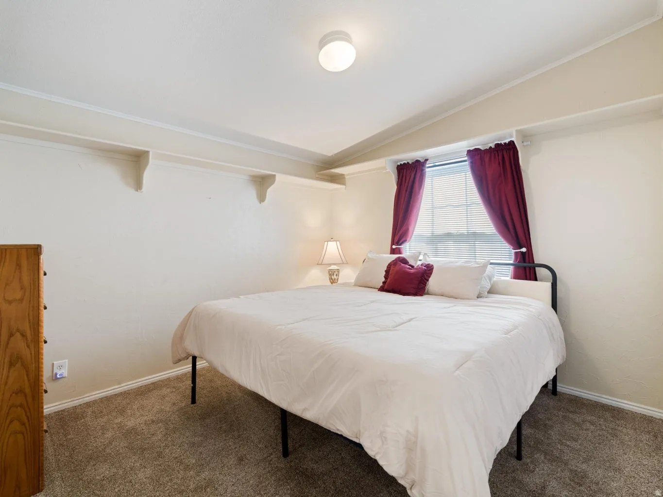 Carpeted room featuring a window with blinds, a prominent ceiling light fixture, and built-in wall shelving