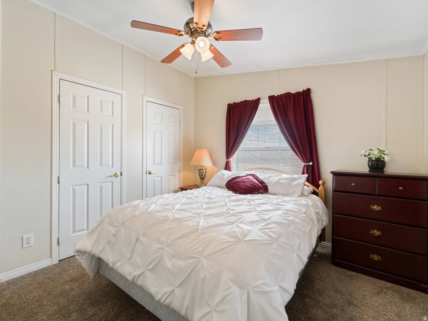 Bedroom featuring carpet flooring, two paneled doors, and a window with blinds