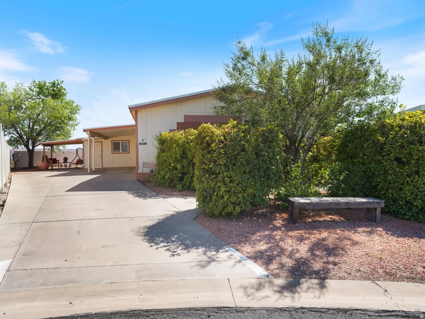 Exterior featuring a covered carport, covered patio, mature landscaping, gravel landscaping, and a concrete driveway
