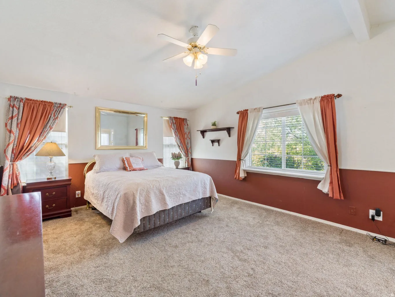 Carpeted interior space featuring a vaulted ceiling and an overhead ceiling fan with lighting