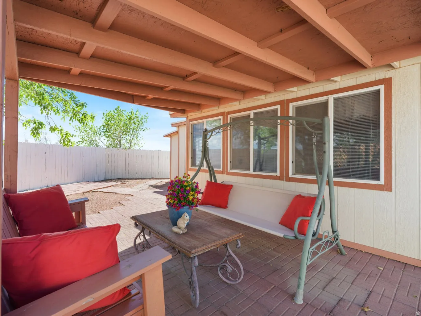 Covered patio featuring a wood-beam ceiling and brick-patterned flooring