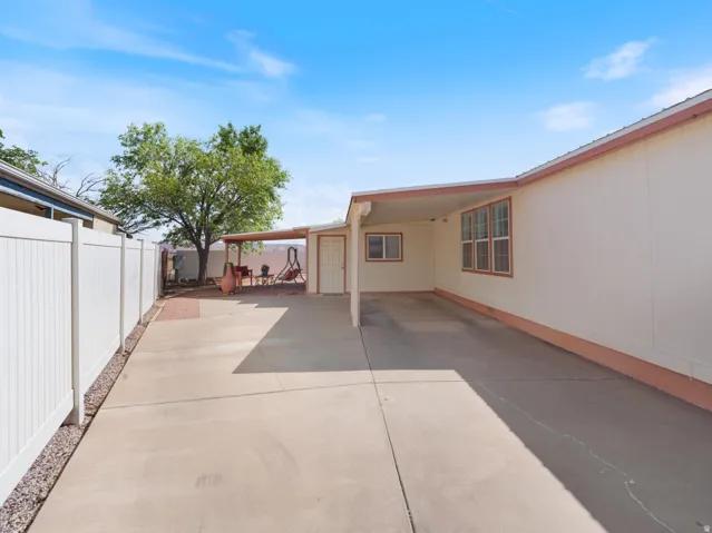 Expansive concrete driveway with an attached carport, featuring multiple windows on the exterior wall