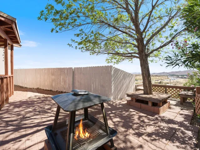 Paver patio featuring a built-in tree surround with bench seating, a white picket fence, and distant mountain scenery