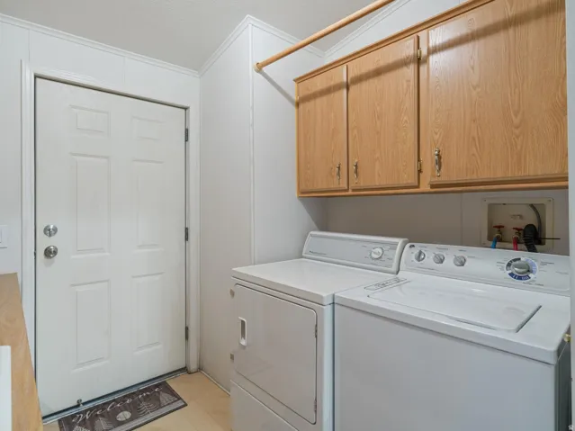 Dedicated laundry area featuring overhead wood-finish cabinetry, a utility rod, and panel-style walls