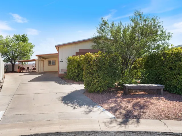 Exterior featuring a covered carport, covered patio, mature landscaping, gravel landscaping, and a concrete driveway