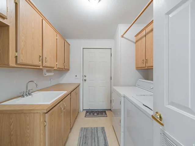 Utility room featuring extensive wood-finish cabinetry, a dedicated sink with a chrome faucet, and a clothes hanging rod